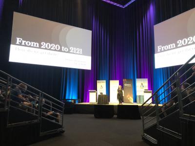 Donna on stage at LCA2020 - Two large screens showing the first slide of her presentation.